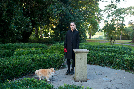 beautiful young woman walking her dog with maize in the background. blackrock park, dublin