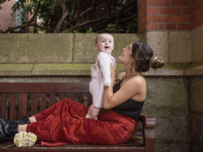 mum holding her new baby on a bench in a stone courtyard in Blackrock