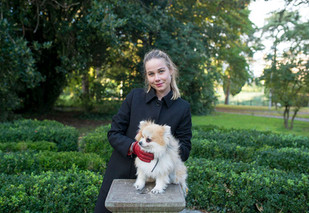 young woman in red leather gloves holding her dog on stone plinth. autumn professional photo shoot dublin