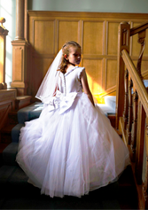 girl in communion dress showing back of dress on stair case