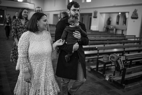 mum and dad crossing church holding baby to be christened