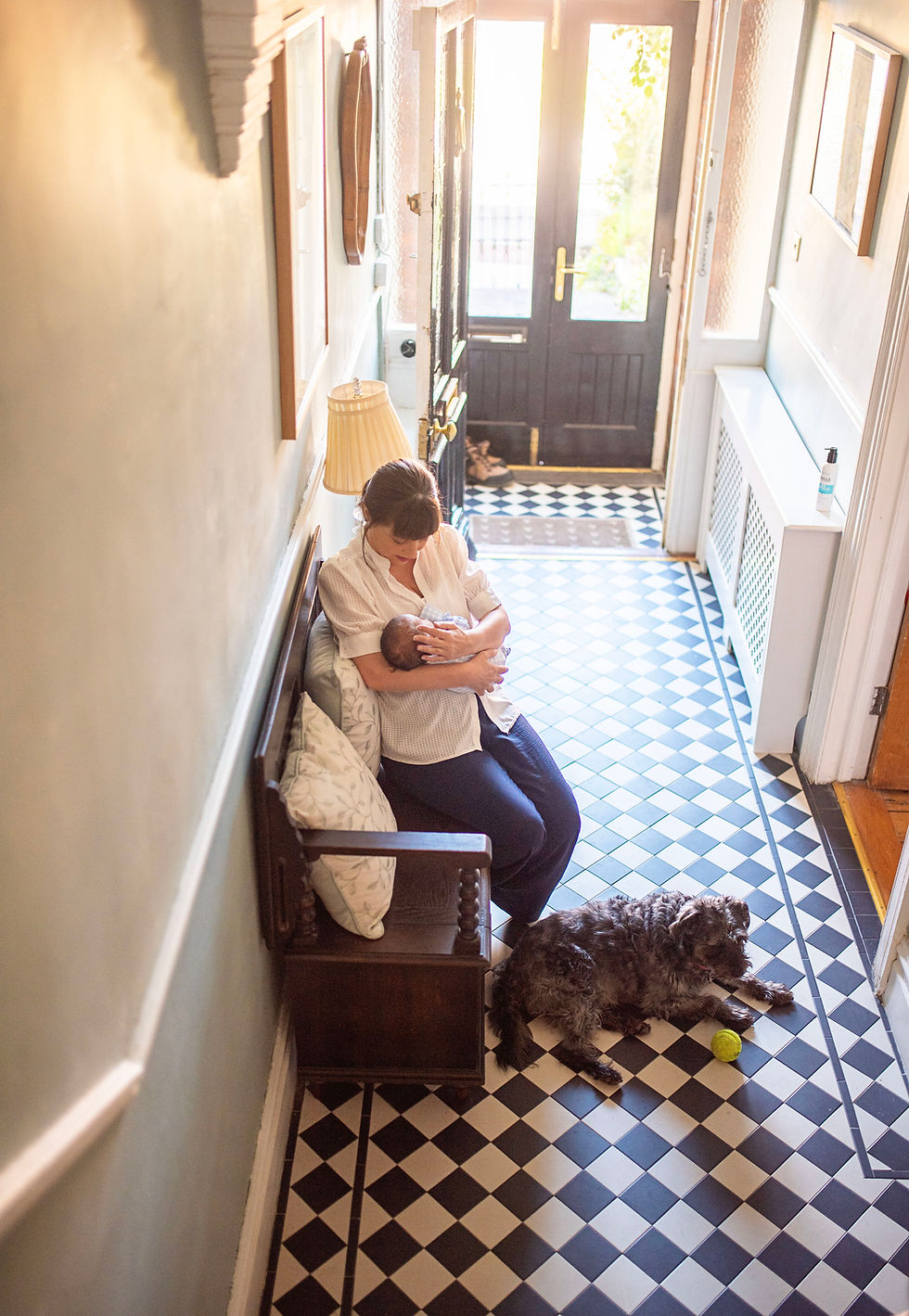 mum holding her newborn son in a hallway with black and white checqured floor