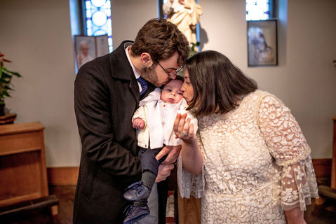mum and dad kissing baby in church