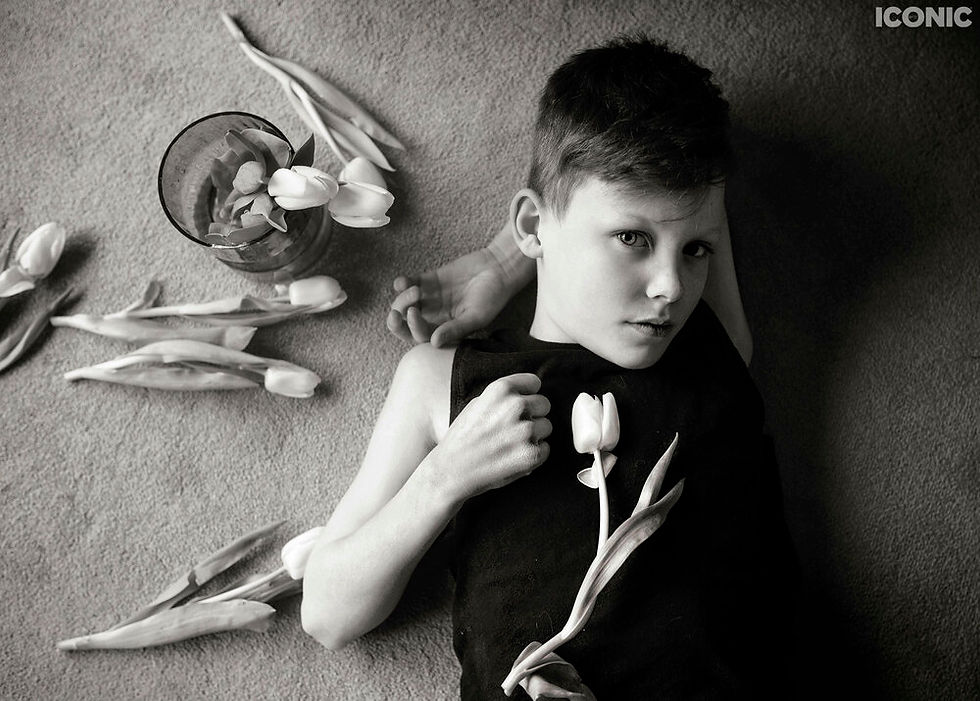 iconic artist portrait, boy with white tulips surrounding his face as he lies on carpet