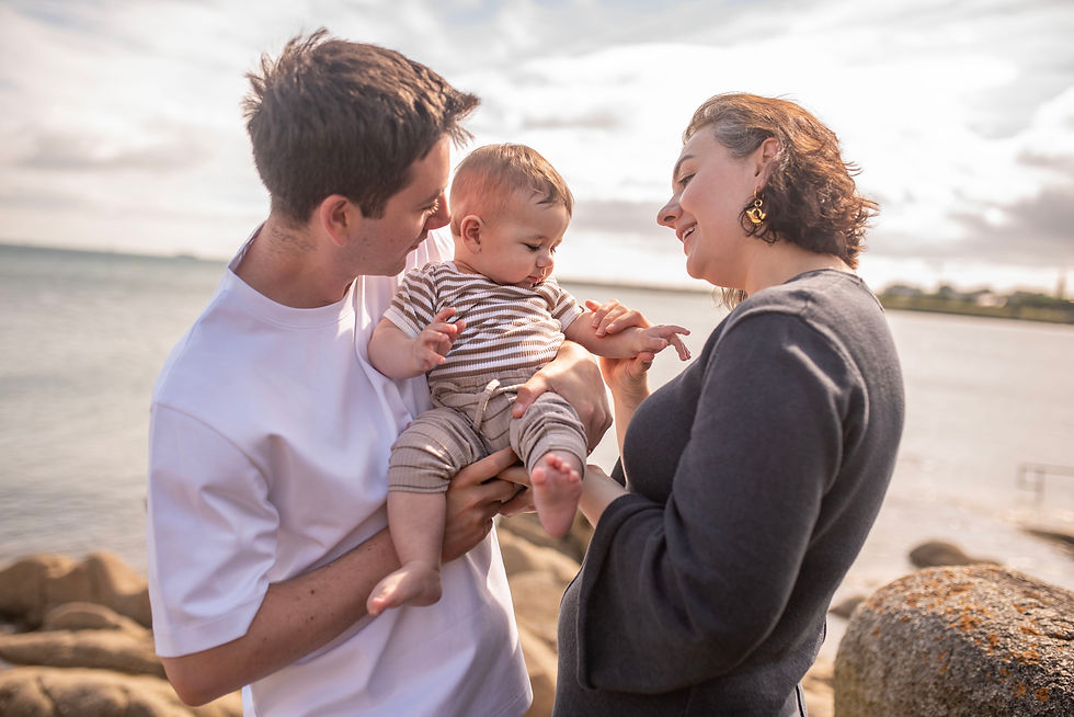 mum and dad holding baby boy with sea in background, close up details of hand holding