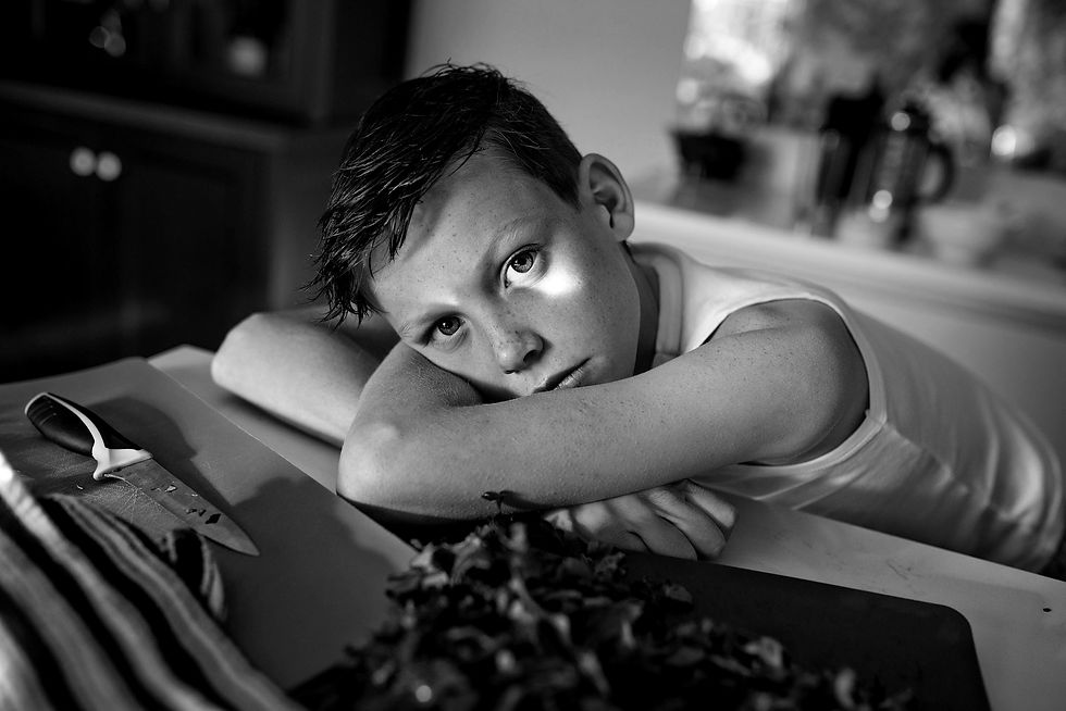 boy leaning across kitchen island with light spot across his eye like a patch