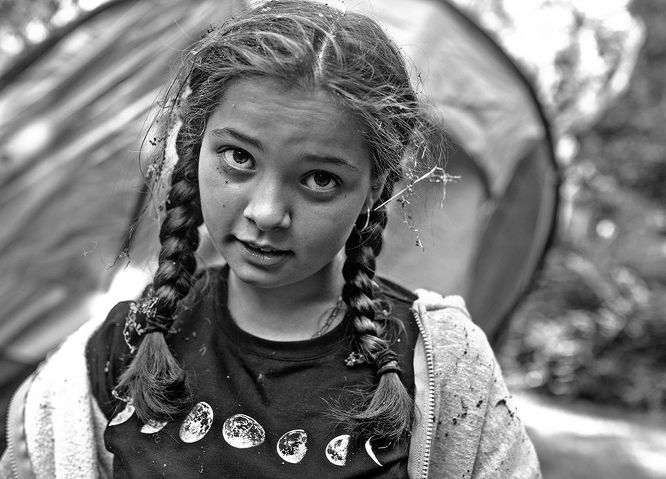 girl with grass and bits of leaf in her hair with incredulous expression on her face
