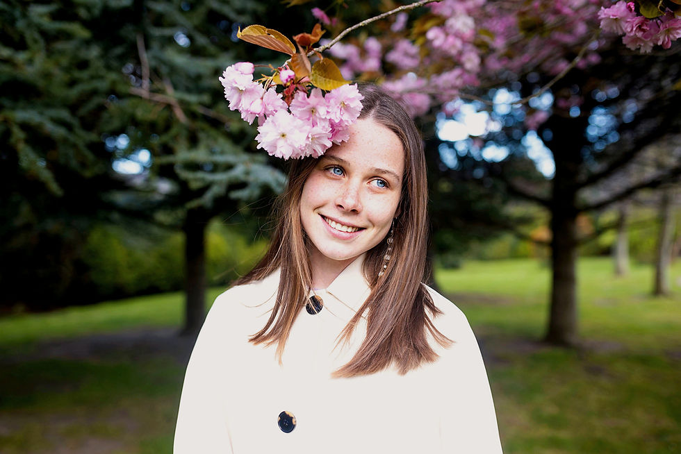 young girl in white coat under a pink blossom tree in the Spring in Blackrcok Dublin