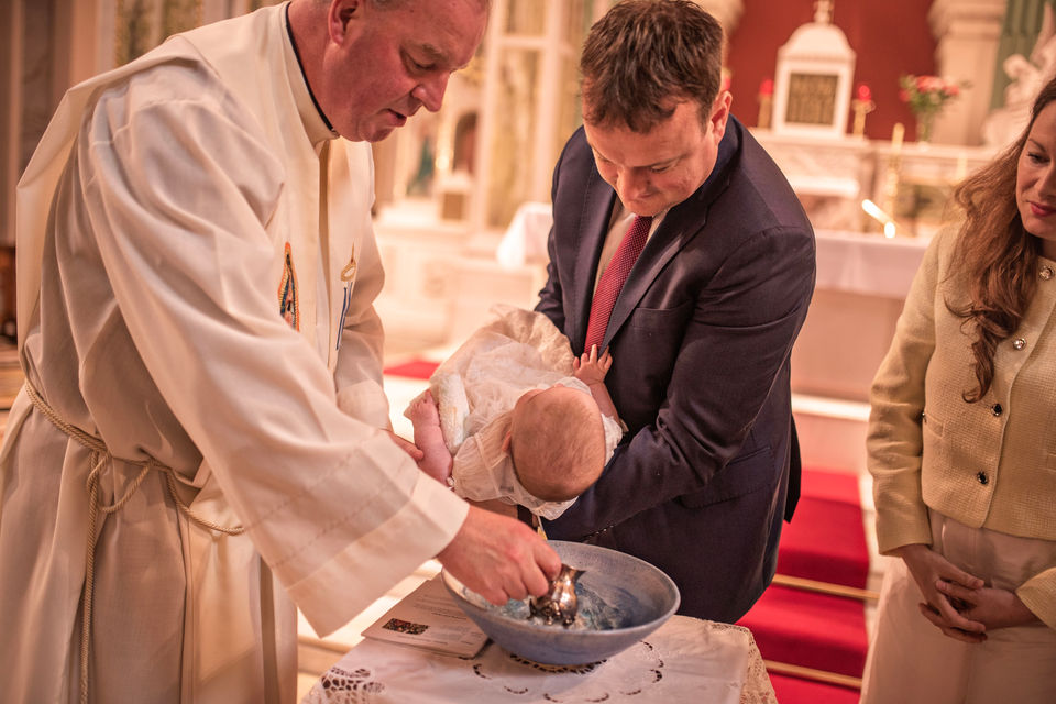 priest blessing baby in the pews