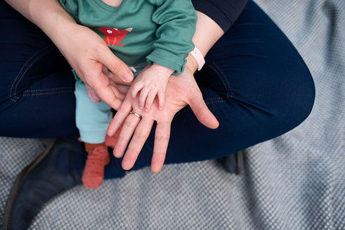 close up of baby's hand on top of mum's hands