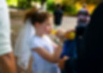 girl in communion dress drinking bottle of Fanta her dad is holding out to her