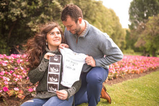 two graduates holding up baby onesie