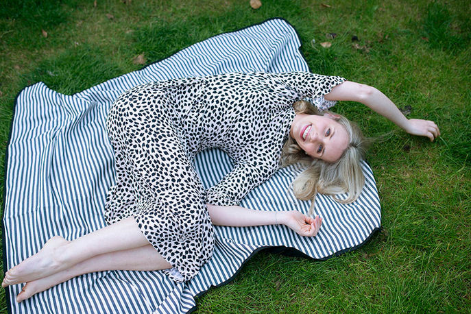 young woman lying on floaty dress on blanket in the garden