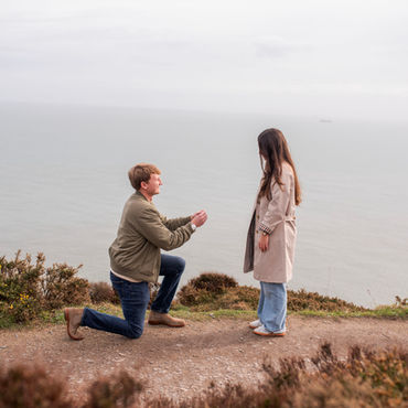 young man proposing to his girlfriend on Howth cliff tops overlooking sea and heather in Dublin