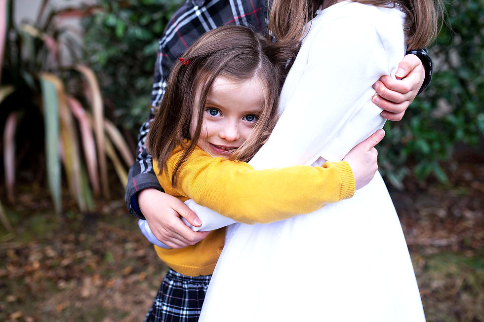 family portrait with siblings hugging in complimentary checked shirts for holy commmunion family photo shoot Dublin at home in garden