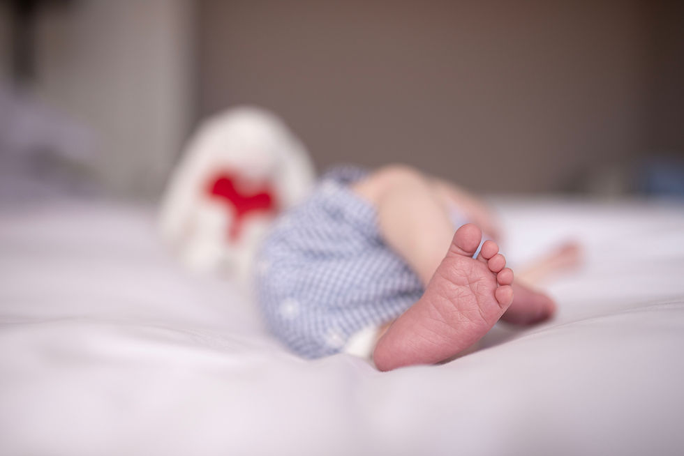 newborn baby foot on master bed with blurry, soft focus backdrop