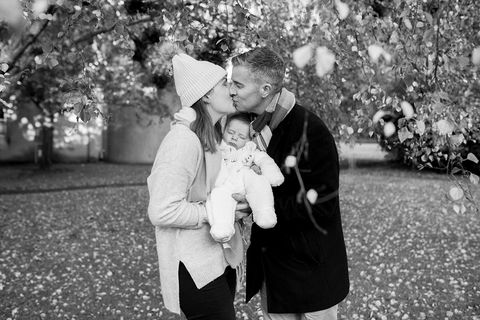 mum and dad kissing and holding newborn baby