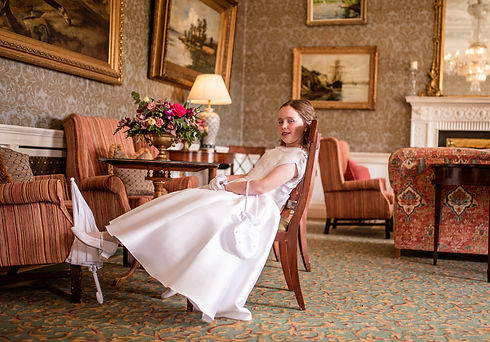 little girl sitting in a chair in an ornate hotel lounge with lampshades and oil paintings