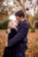 couple hugging and gazing into each others eyes, surrounded by autumn leaves