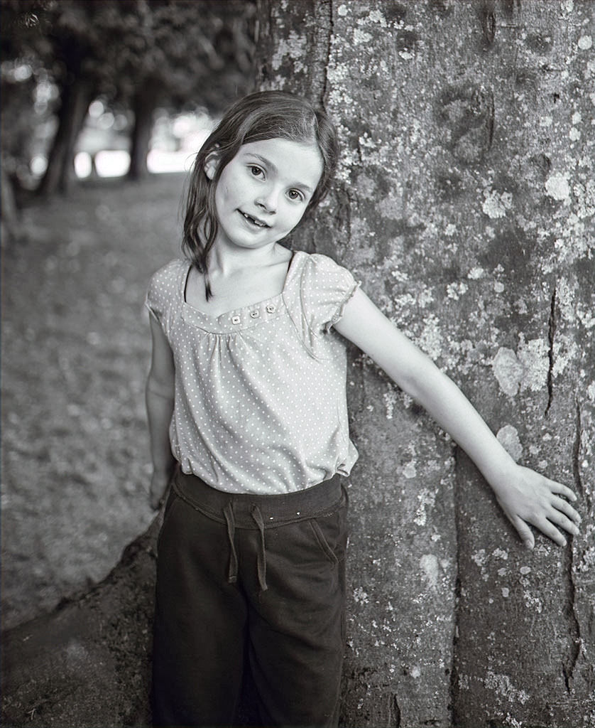 black & white portrait of girl with arms around tree