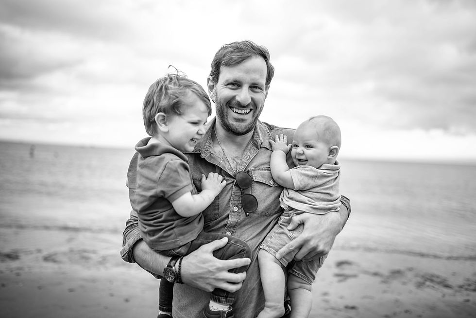 dad holding two kids in his arms including smiling baby