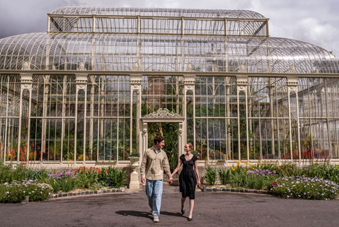 couple in front of a large victorian green house