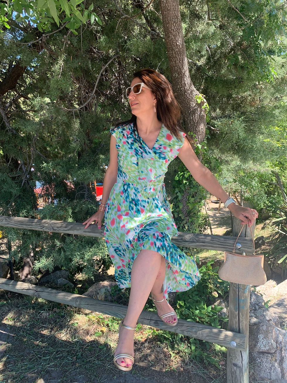 Mujer sentada con vestido en suaves tonos verdes claritos con volantes estilo pañuelo