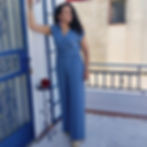 Mujer con un favorecedor mono azul cielo apoyada sobre la pared con fondo blanco y cinturón en el mismo tono del mono