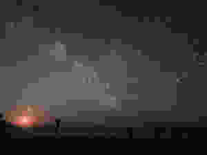 A dark starry sky with the milky way visible - below is the sea with island just discernable