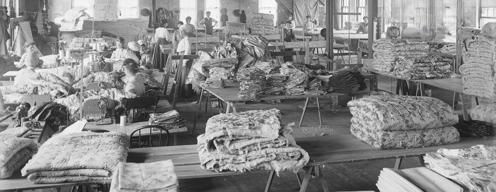 Mattress factory employees in the sewing room working on comforts