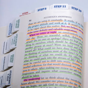 AA Big Book open to page 86 with color-highlighted text and Step tabs