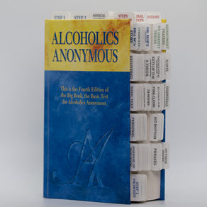 Tabbed AA Big Book at an angle showing full columns of pre-labeled tabs