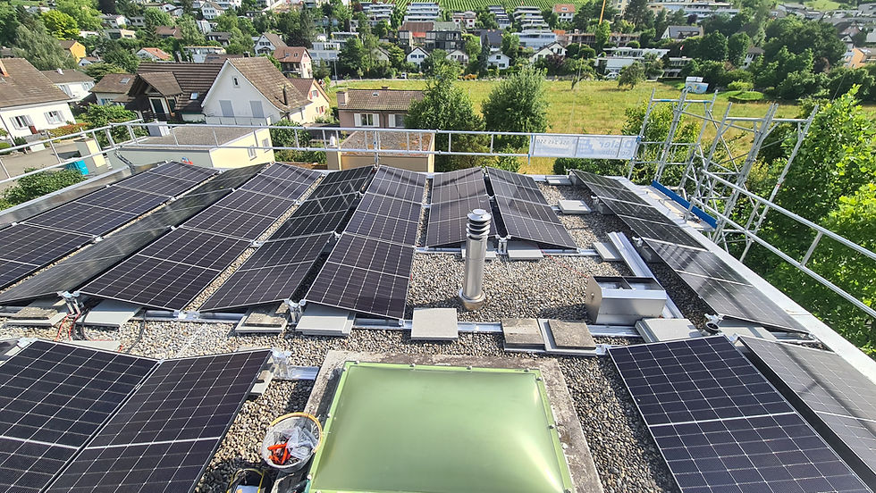 Photovoltaikanlage auf einem Flachdach mit mehreren Solarpanels und Blick auf umliegende Wohnhäuser.