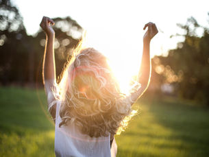 A woman in grass with a sunset
