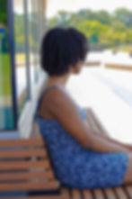 Contemplative woman on bench by a window, emphasizing thoughtful solitude.