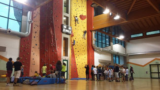 Arrampicata indoor: persone che scalano una parete alta. InMountain Guides