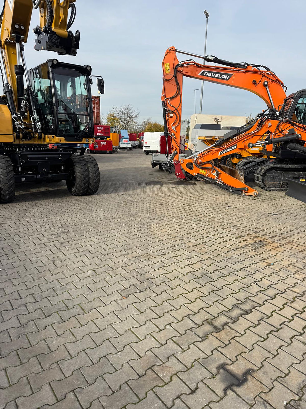 Gelber und oranger Bagger auf einer Pflasterfläche