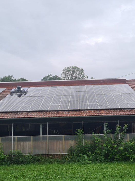 Mitarbeiter reinigt Solarmodule auf Dach mit Hebebühne