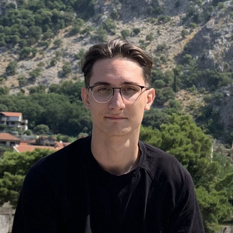 Artem Shyposha with glasses, smiling in front of a picturesque mountain landscape.
