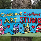 Colorful sign on a tree that says conscious creation art studio with four cute creatures