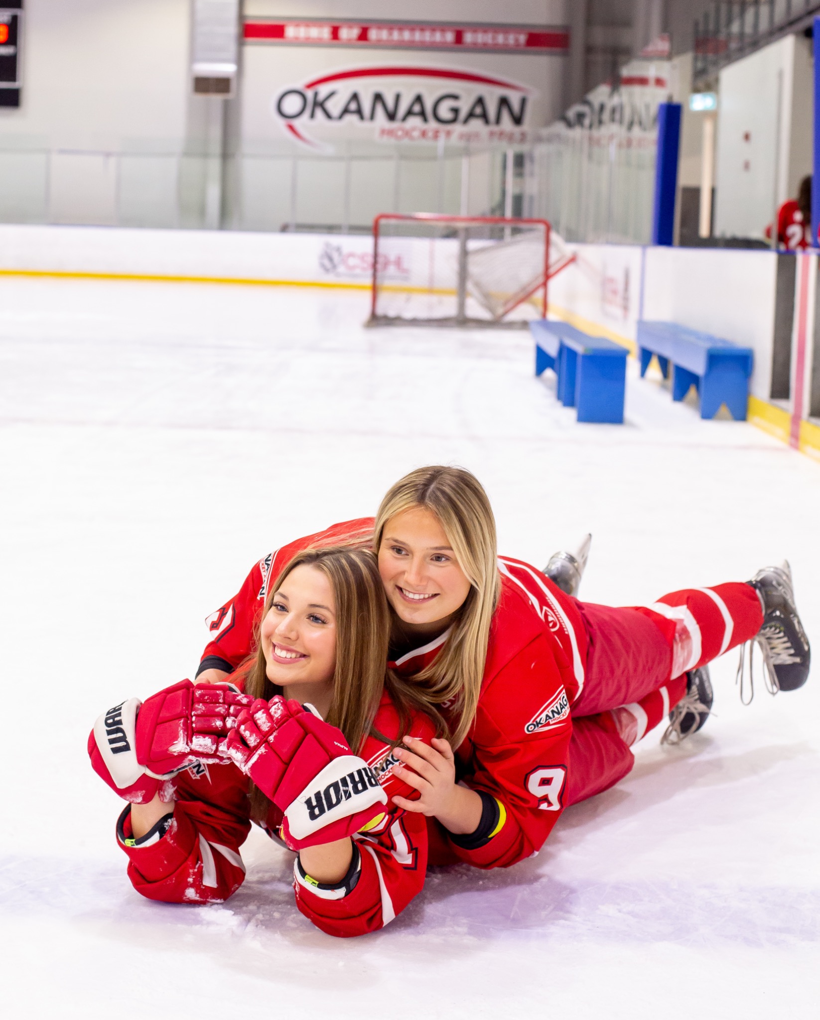 Two Okanagan hockey players in red jerseys posing together on the ice