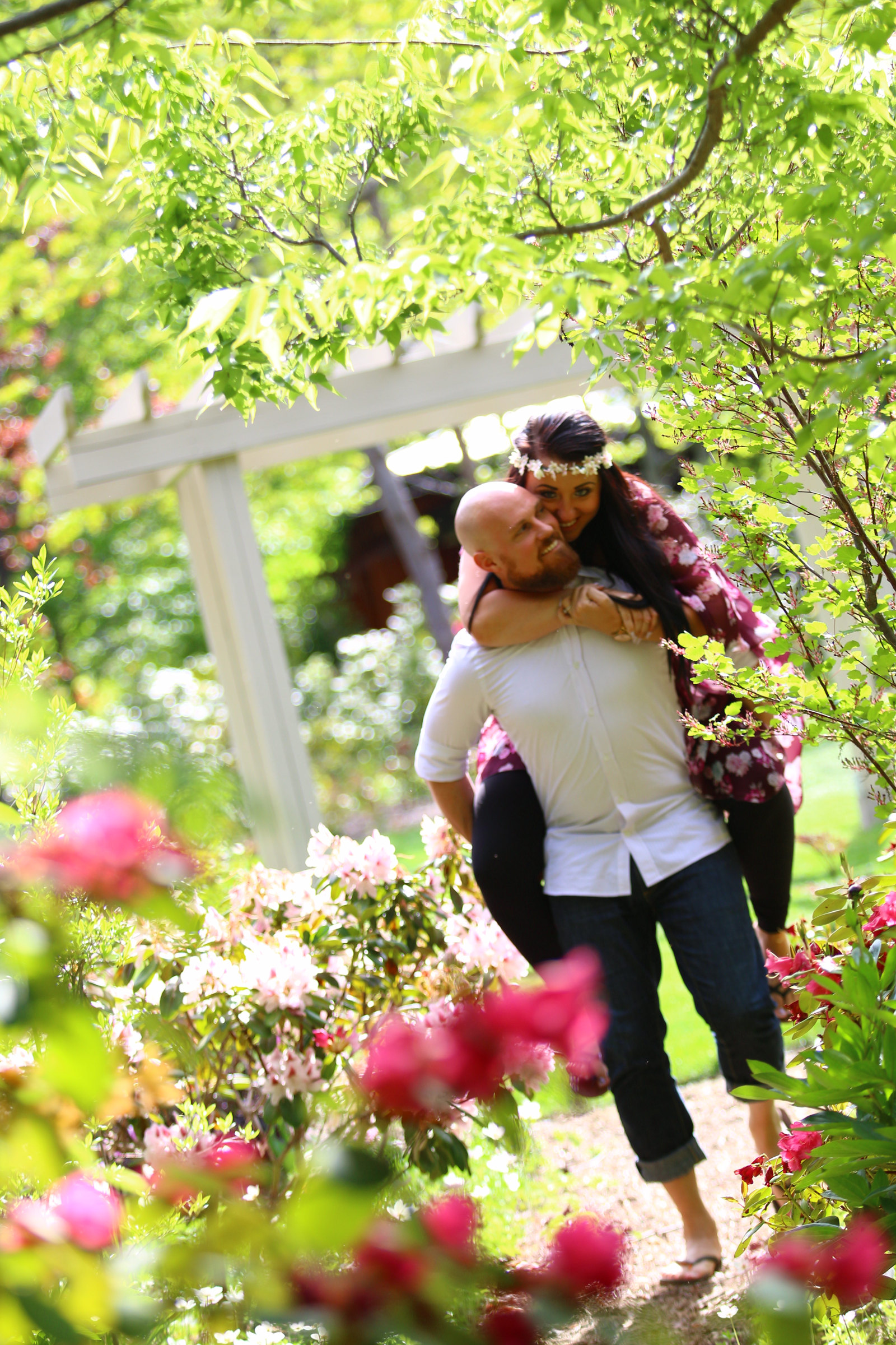 Outdoor couples portrait surrounded by pink flowering branches and a garden archway