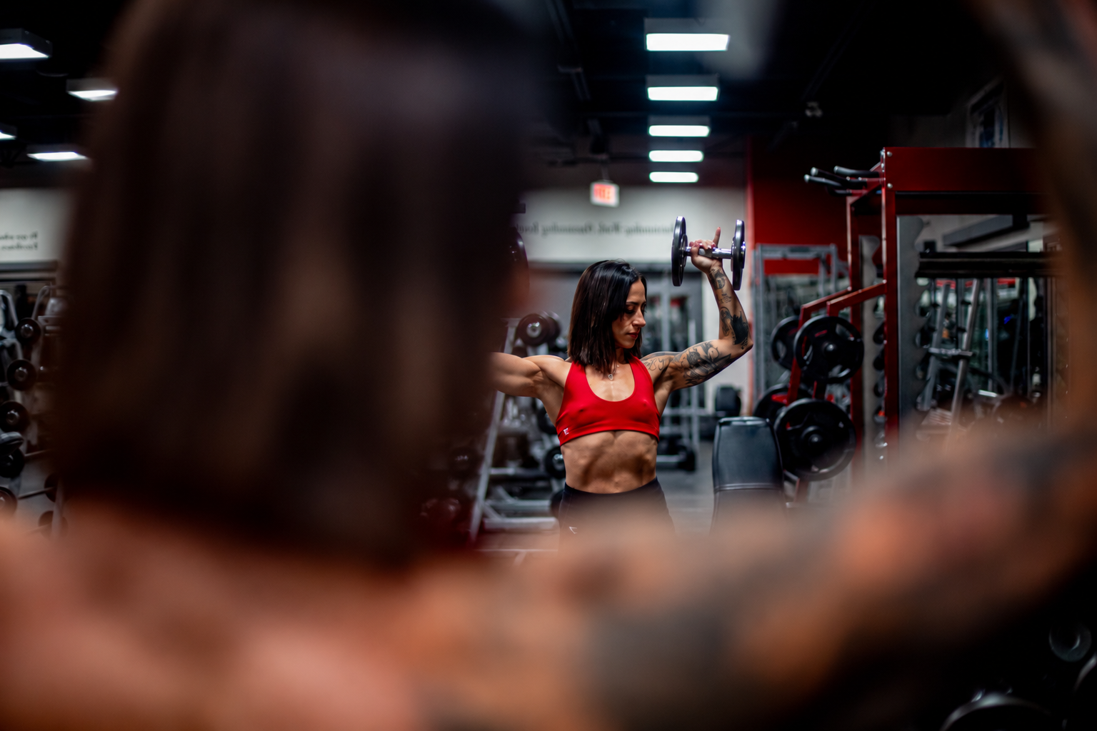 Female athlete training with dumbbells in a gym with cinematic lighting and framed foreground