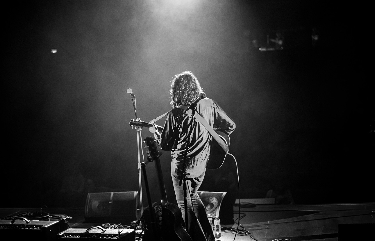 Black-and-white concert photography of a musician performing on stage under a spotlight