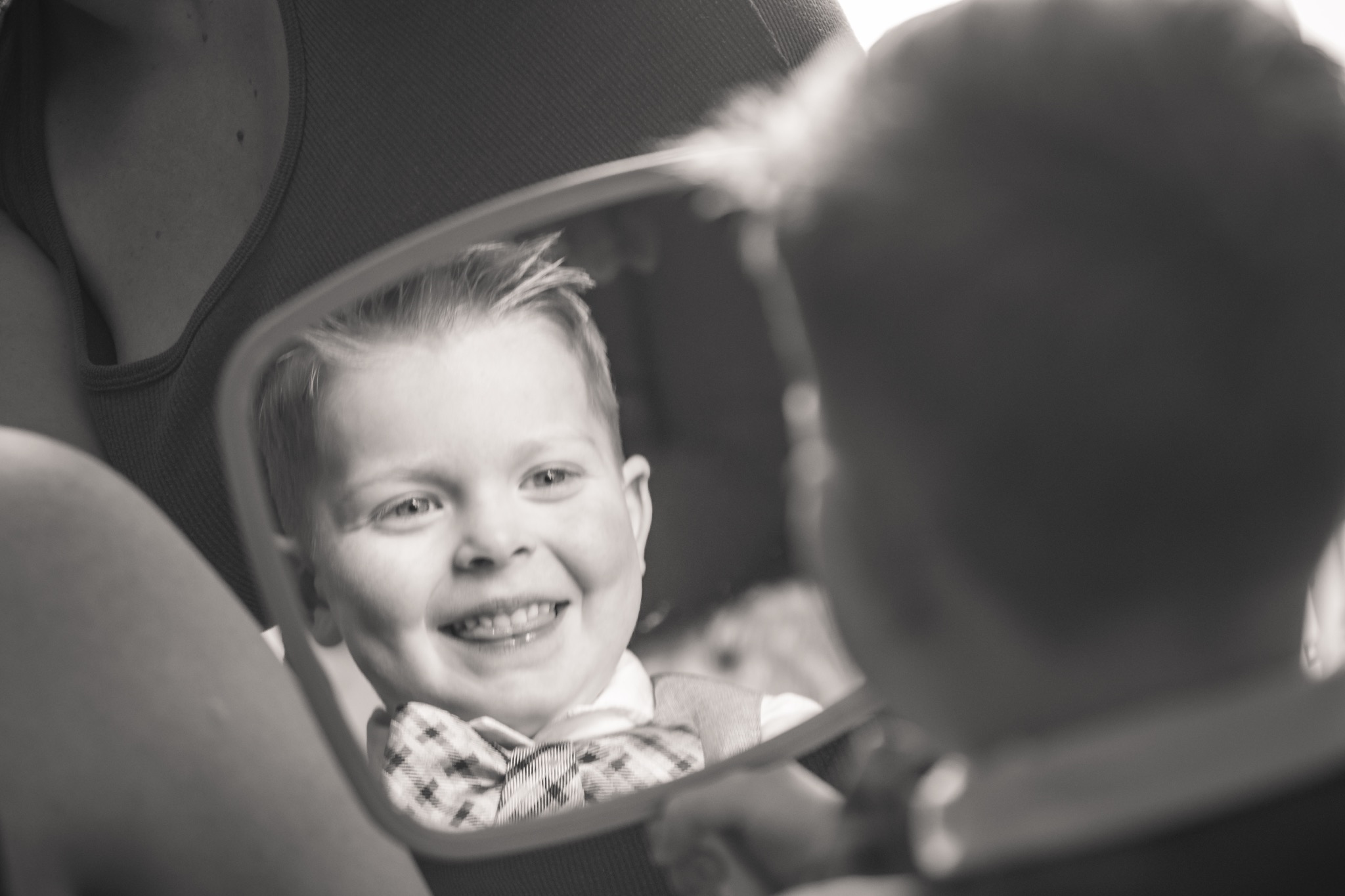 Black-and-white reflection portrait of a smiling boy seen in a mirror