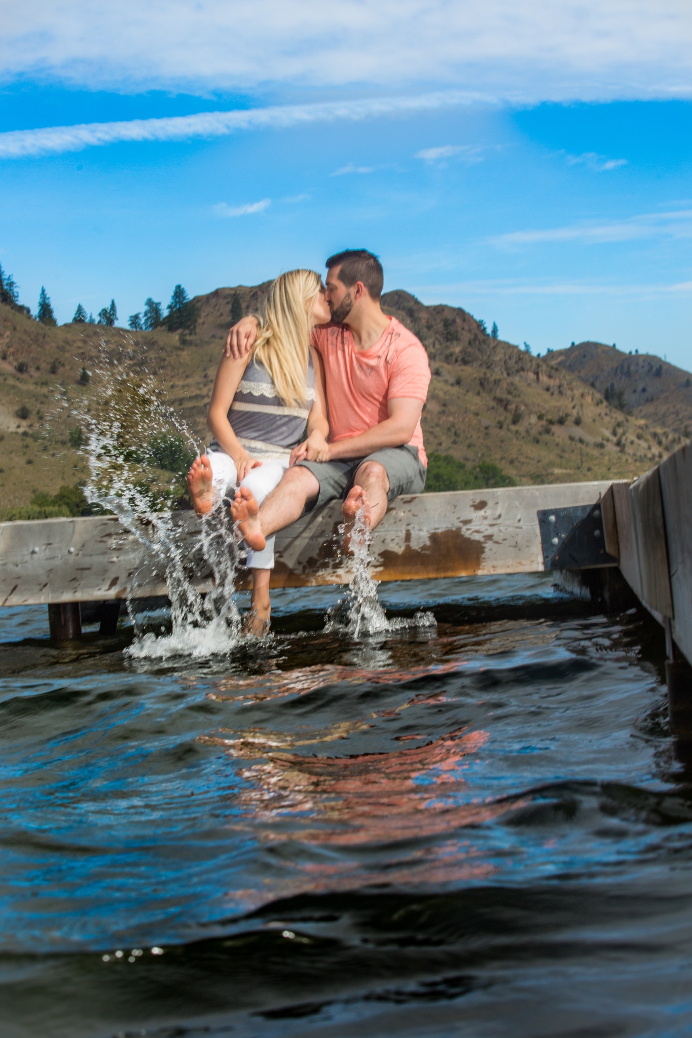 Couple sitting together and splashing their feet in the lake beside a dock
