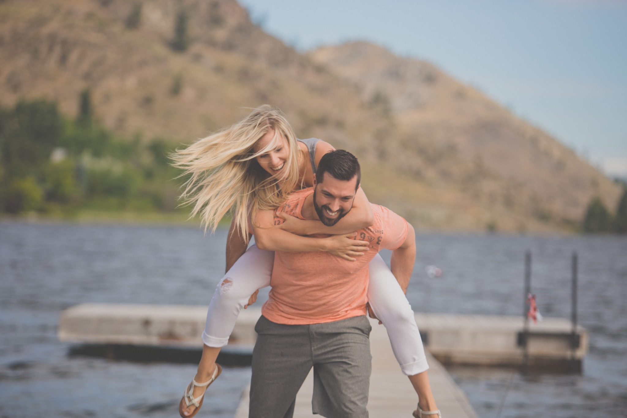 Laughing couple enjoying a playful piggyback ride beside the water