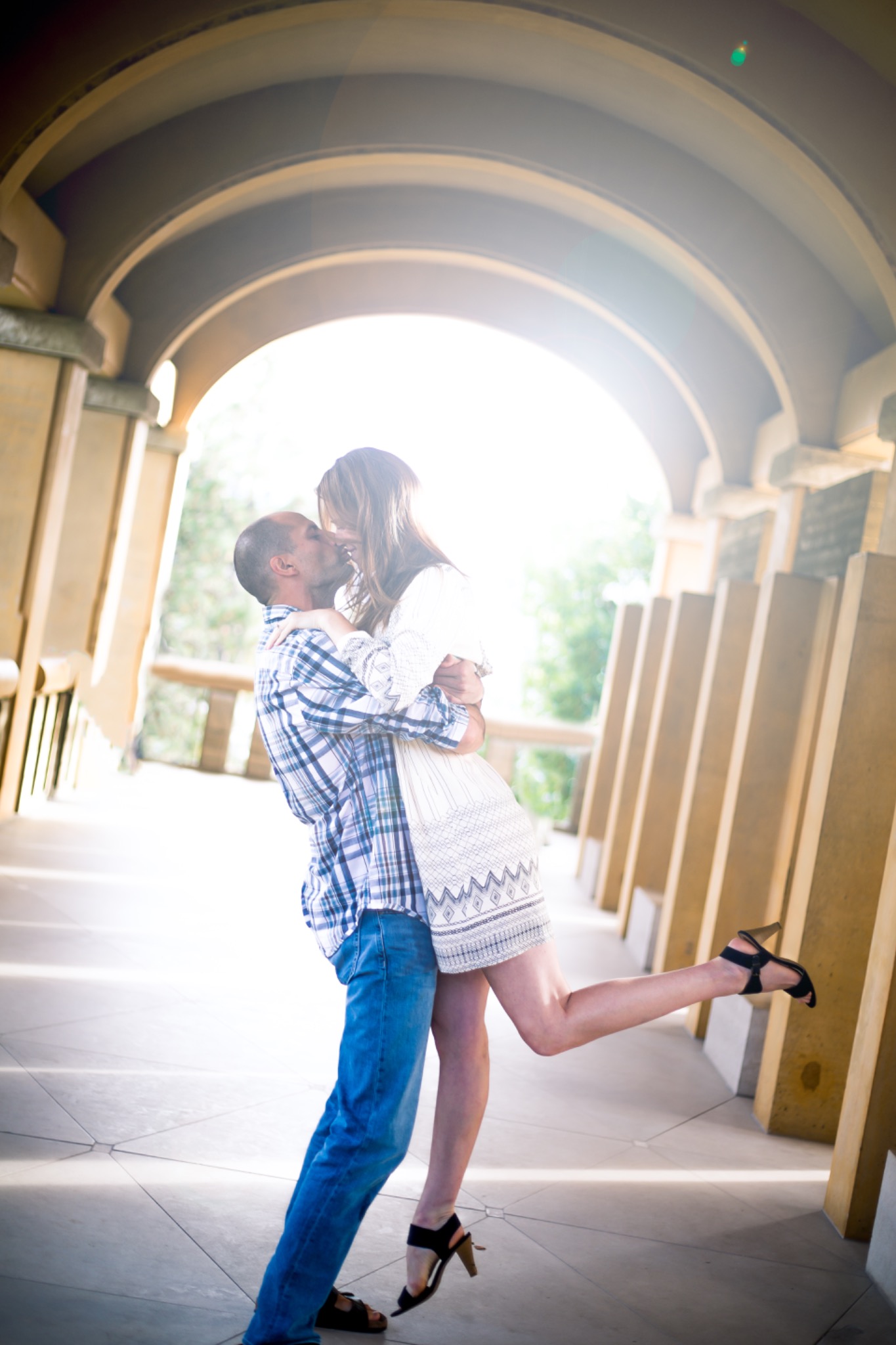 Couple kissing beneath a series of elegant arches during a romantic portrait session