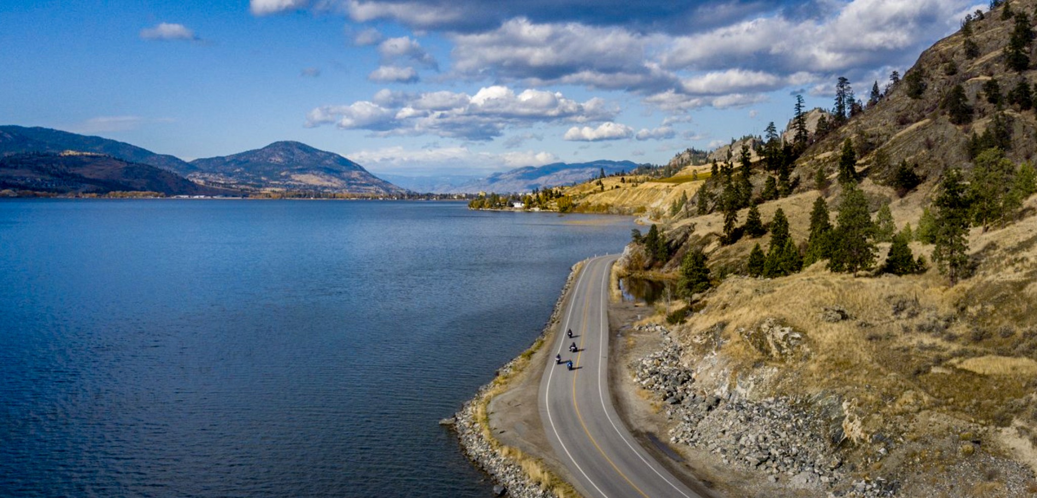 Aerial landscape photograph of a road winding beside an Okanagan lake