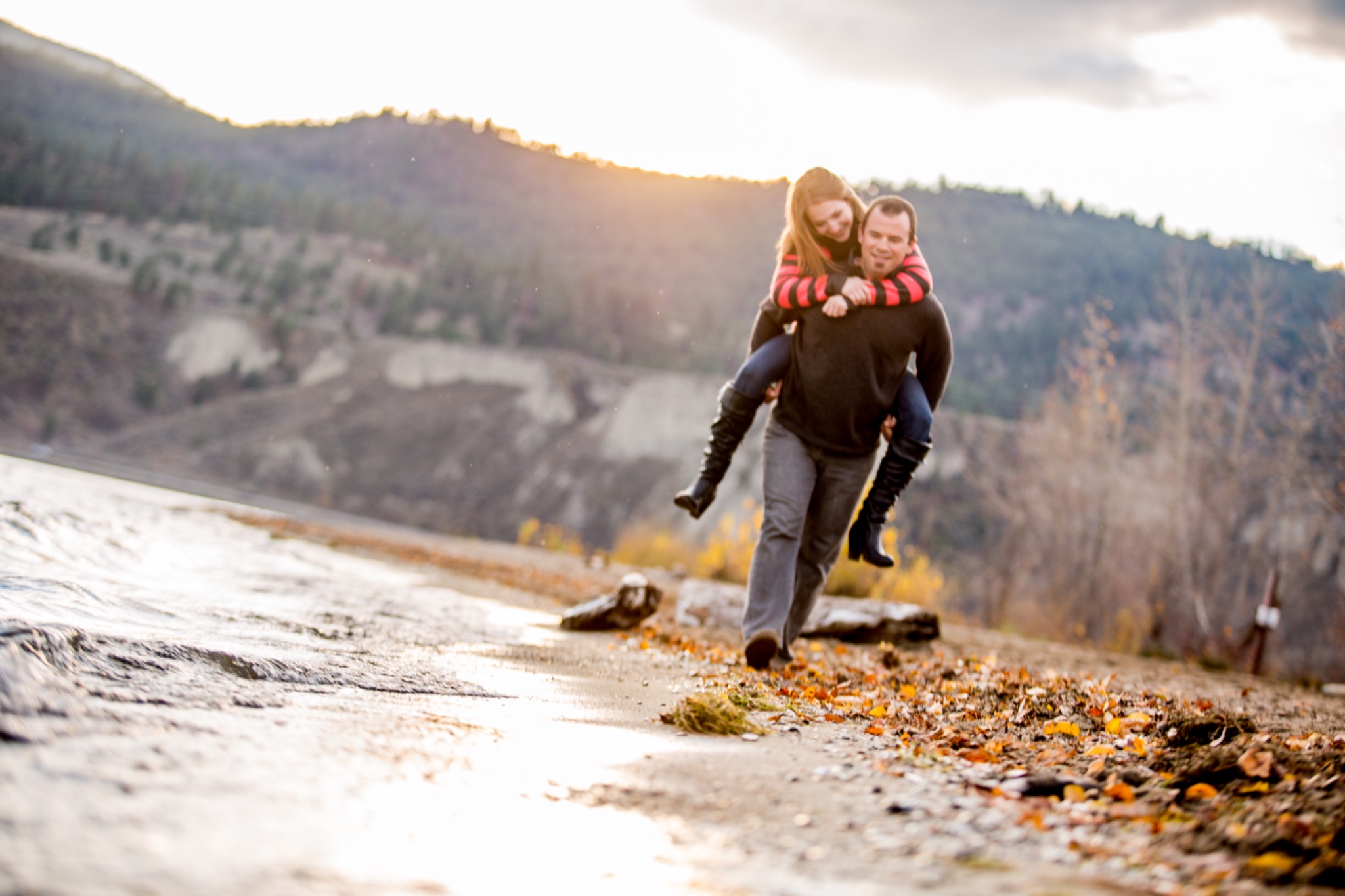 Playful couple piggybacking on an autumn lakeside path